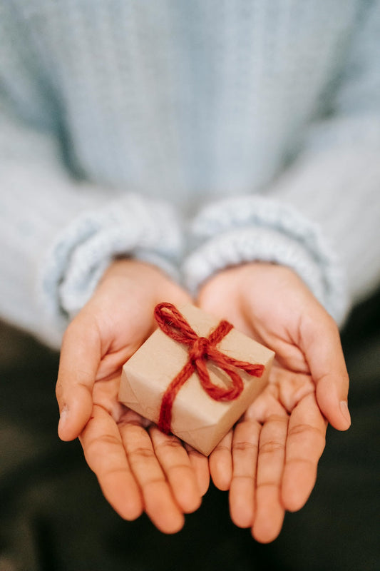 Open palms giving a small wrapped gift