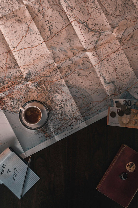 Coffee mug on a map with 'Where to next' written on a notepad