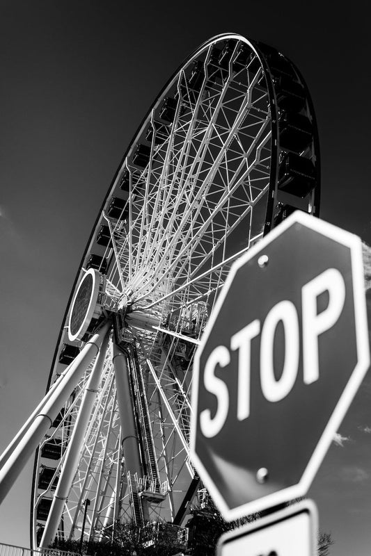 Stop sign in front of a Ferris wheel