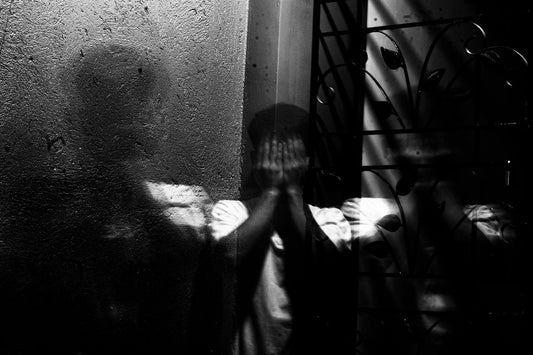 Person in corner with hands covering their face