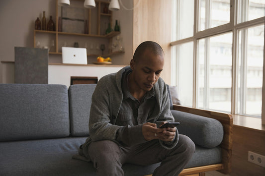 Man on the edge on the couch texting with a worried expression