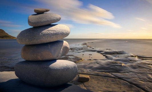 Round rocks stacked with the ocean in the background. 