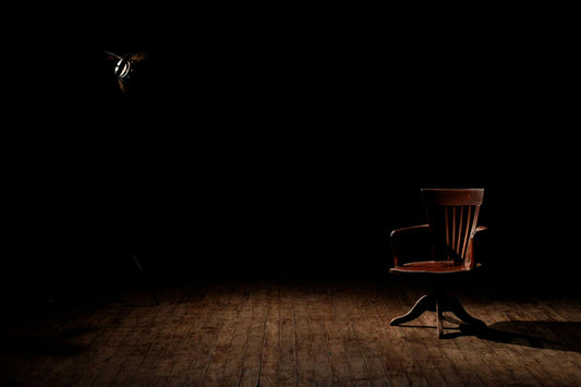 An empty chair in the spotlight on the stage.
