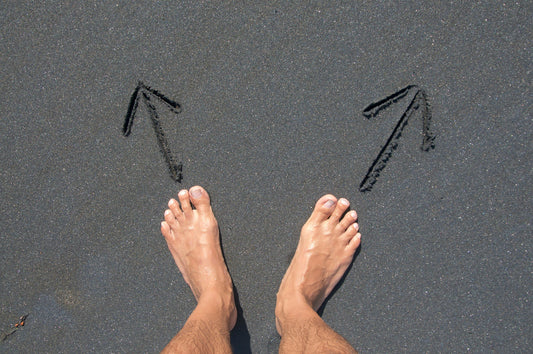 Feet in sand with arrows pointing opposite directions.