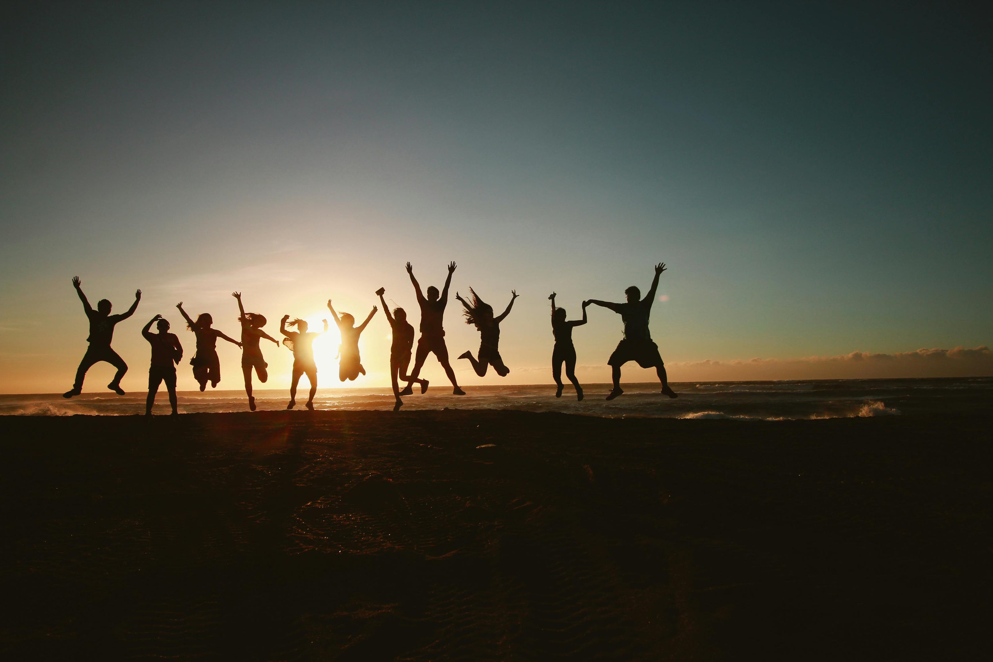 Silhouettes of people jumping together with a sunset in the background