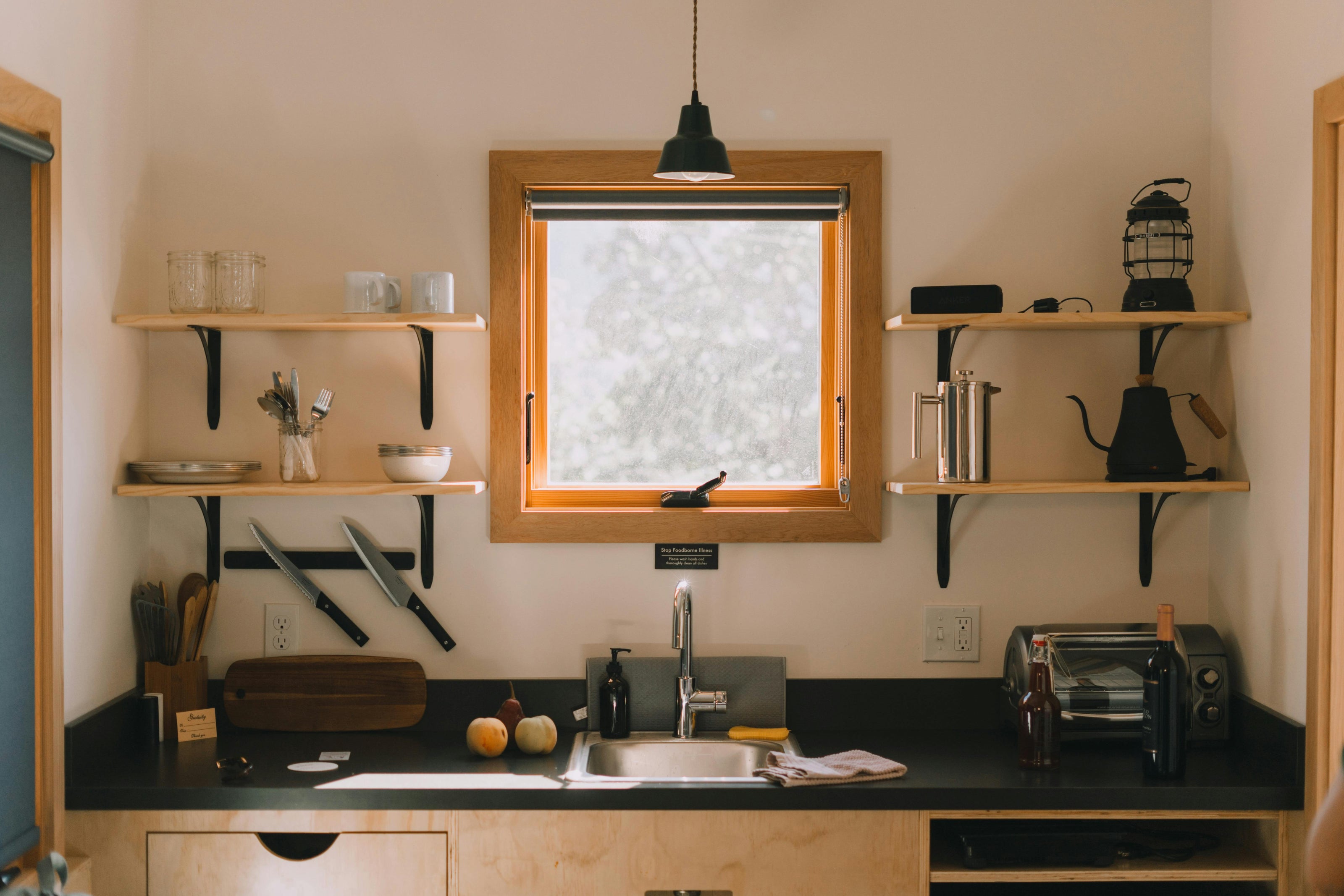 Kitchen with wooden shelves, window, and black countertop