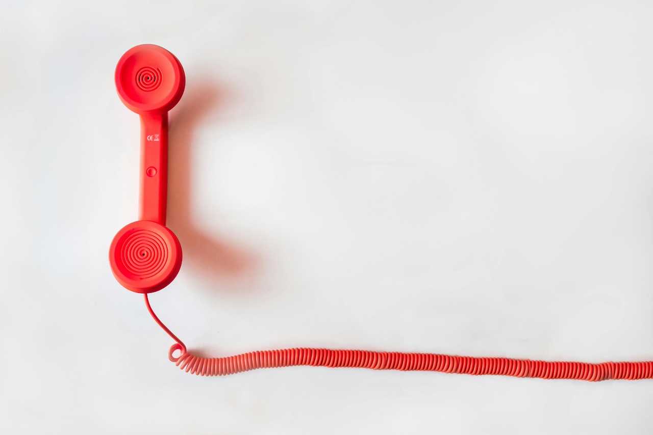 Red telephone with a red cord on a white background